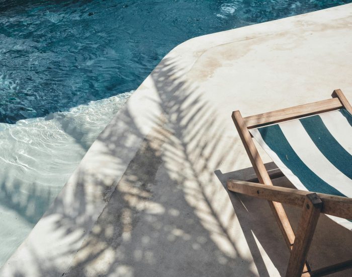 Serene poolside lounger with palm shadows, perfect for summer relaxation in Bali.